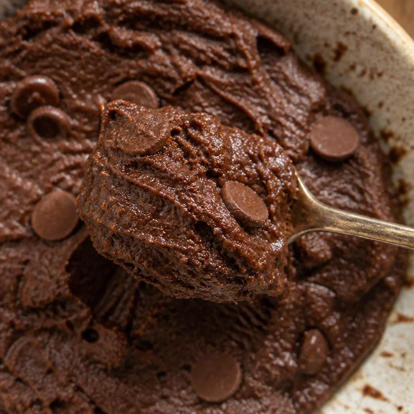 Bowl of edible chickpea brownie batter with chocolate chips and ingredients